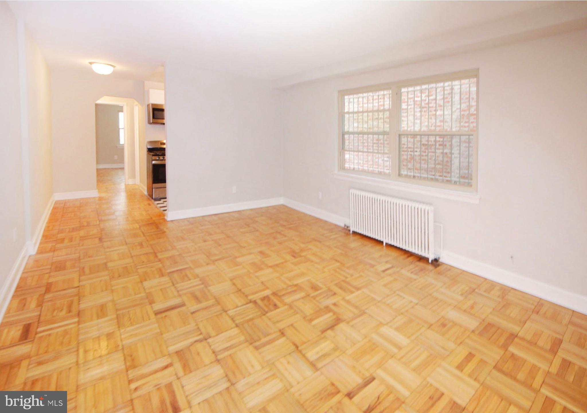 a view of an empty room with kitchen and a window