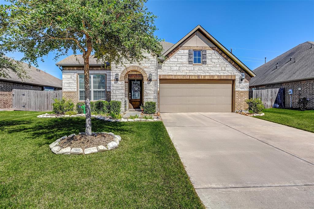 This single-story Lennar home boasts a timeless stone and brick exterior with a welcoming arched entry and lush landscaping, creating a warm and inviting first impression.