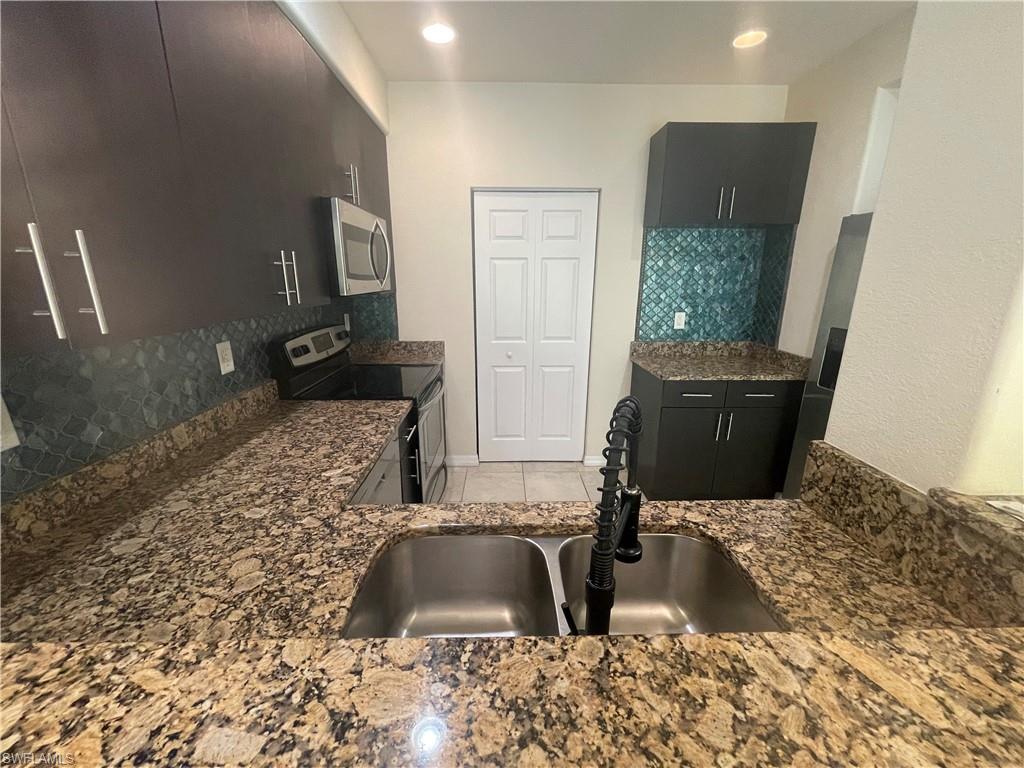 a view of a kitchen with granite countertop a sink and a stove top oven