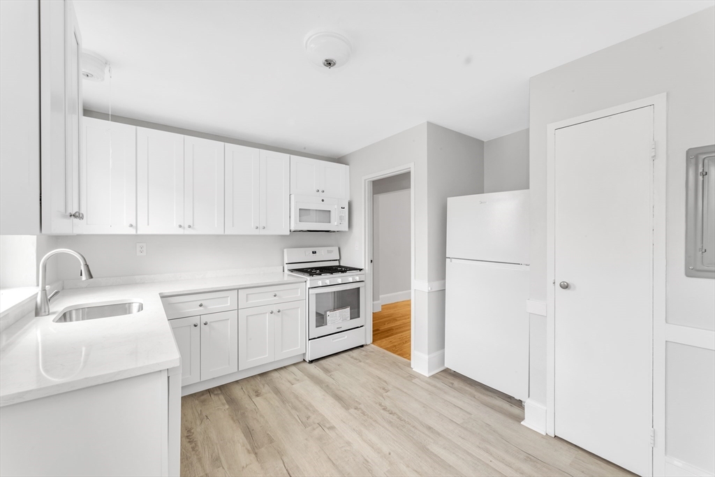 a kitchen with a sink a refrigerator and white cabinets