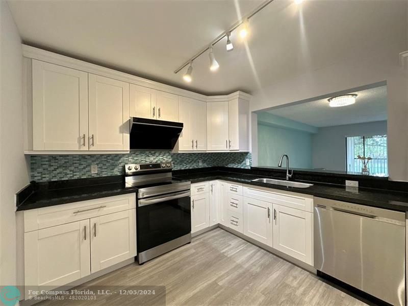 a kitchen with granite countertop white cabinets and black appliances