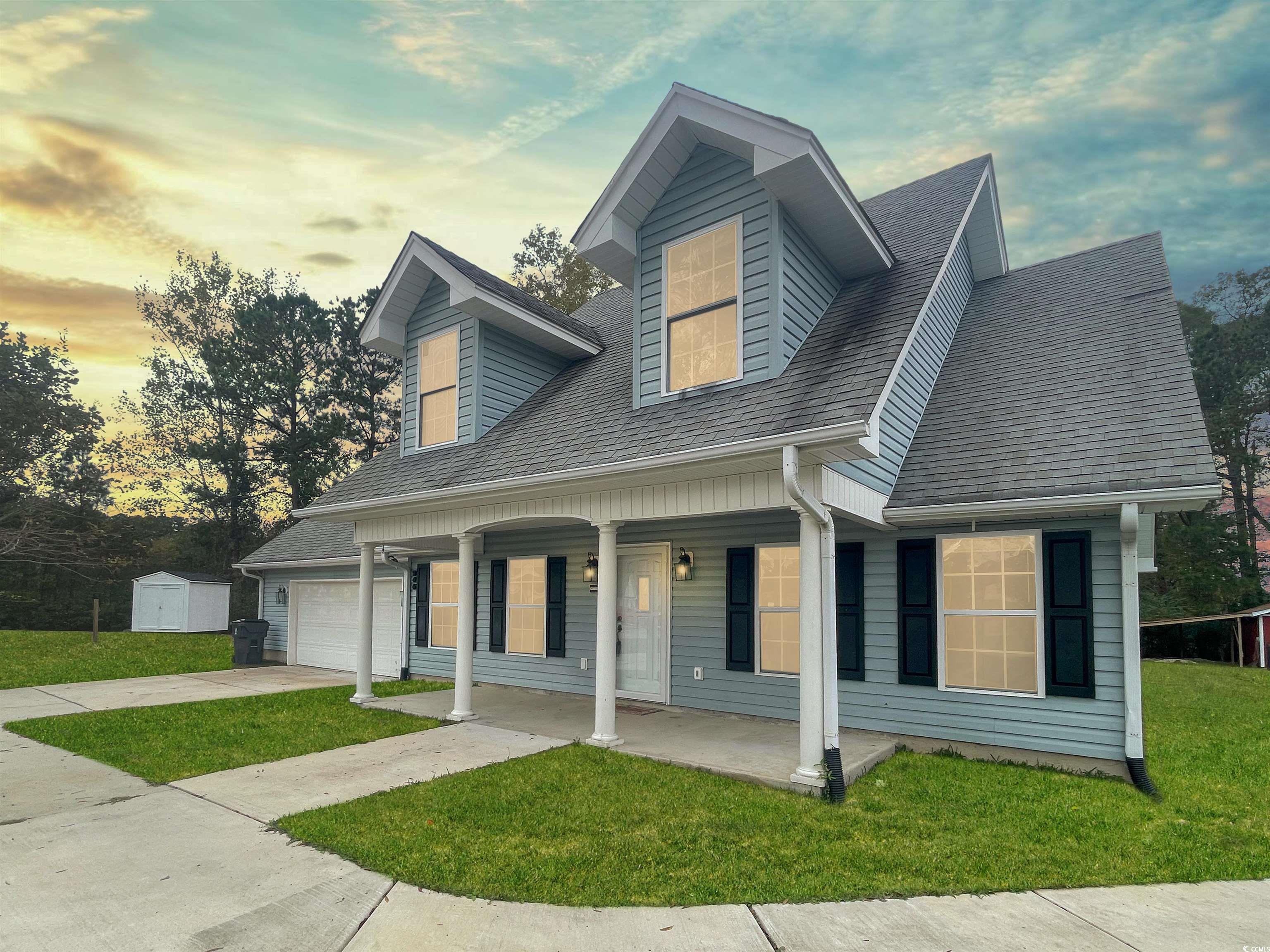 Cape cod-style house with a yard, a storage unit,