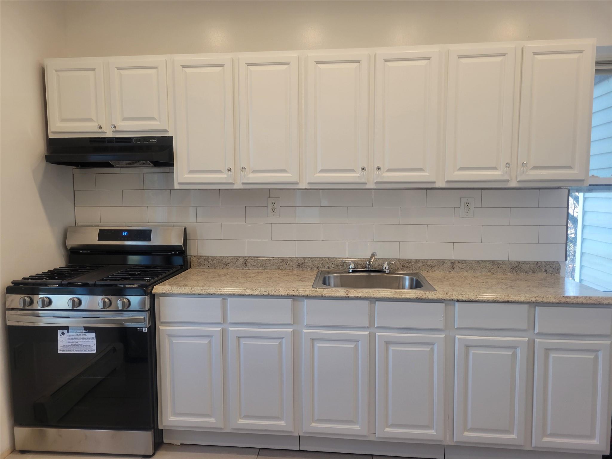 a kitchen with granite countertop white cabinets and stainless steel appliances