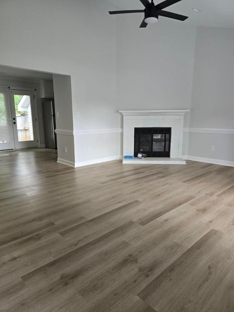 an empty room with wooden floor a fireplace and windows