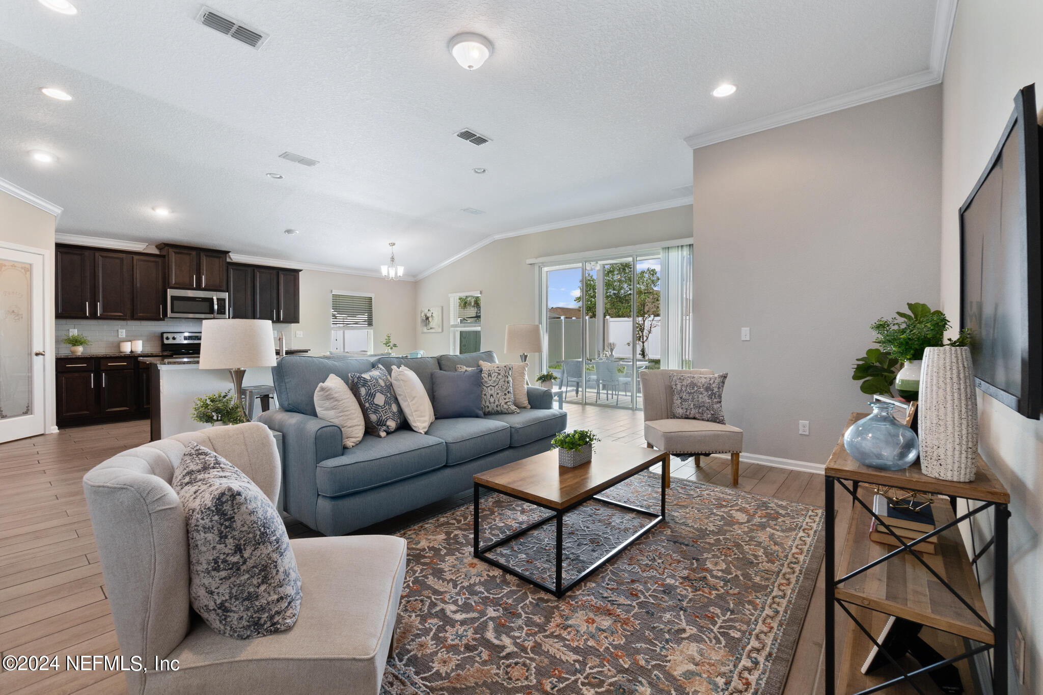 a living room with furniture a kitchen view and a potted plant