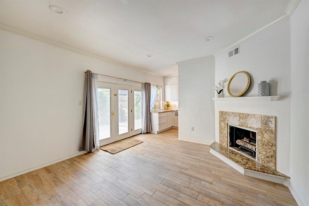 a view of an empty room with wooden floor fireplace and a window