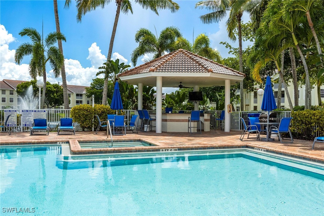 a view of a swimming pool with lawn chairs under an umbrella