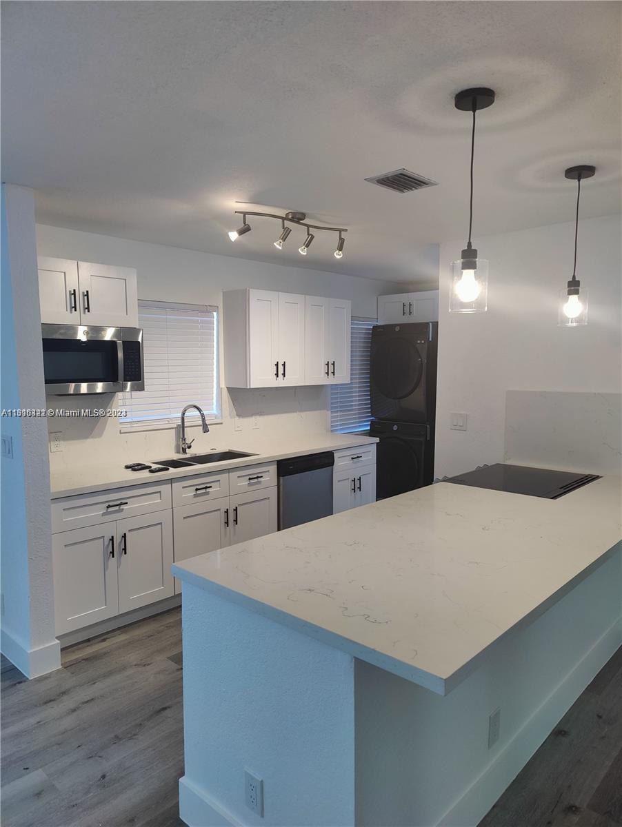 a kitchen with kitchen island a sink stainless steel appliances and cabinets