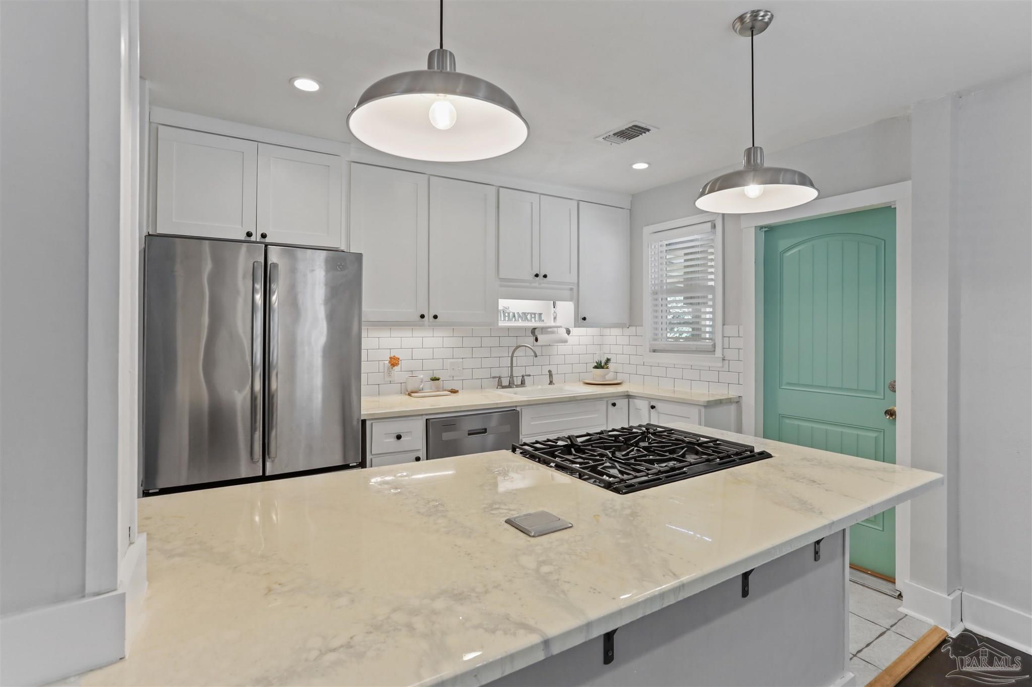 a kitchen with a refrigerator a stove a sink and cabinets