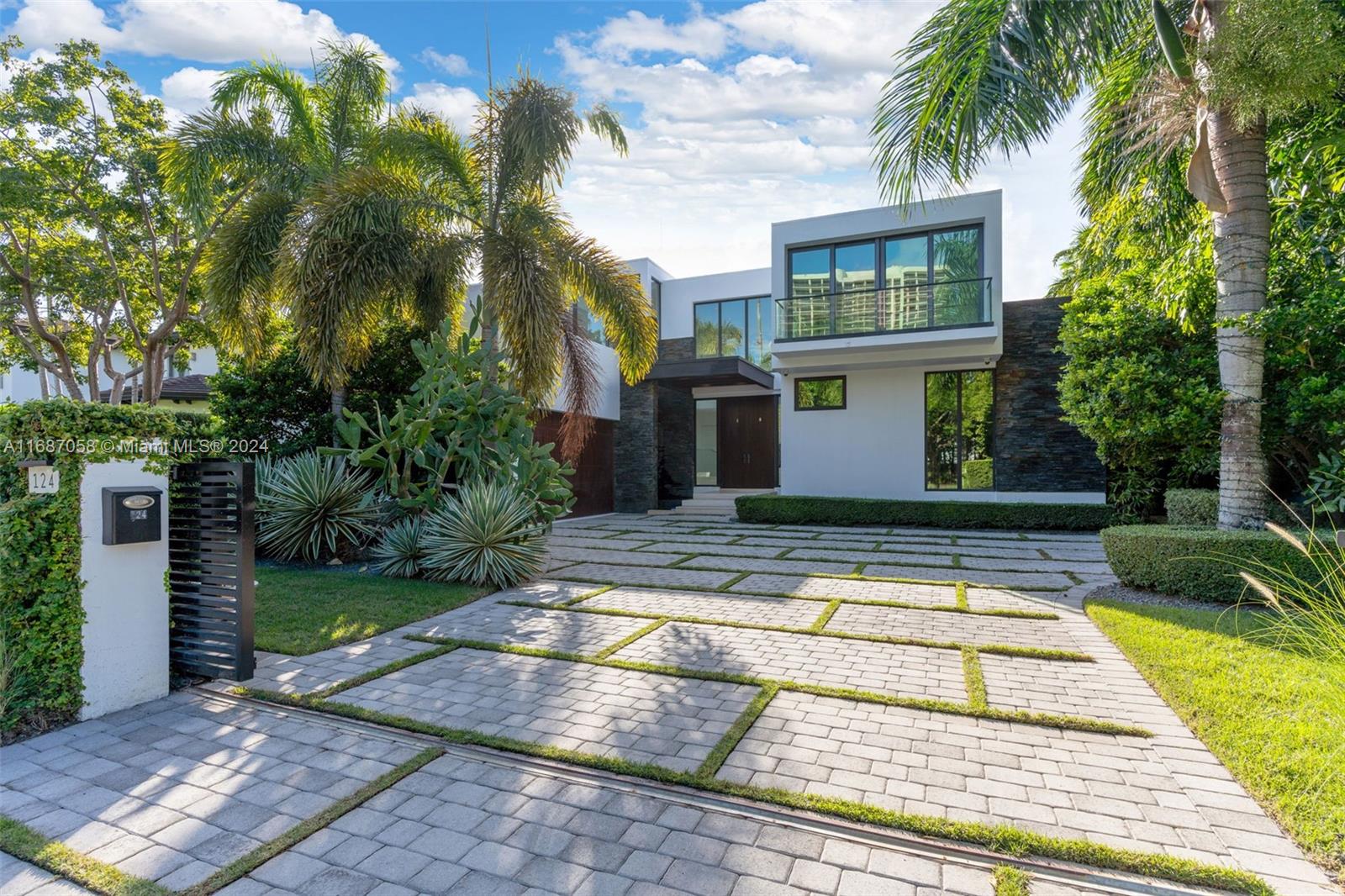 a view of a white house with a yard plants and palm trees