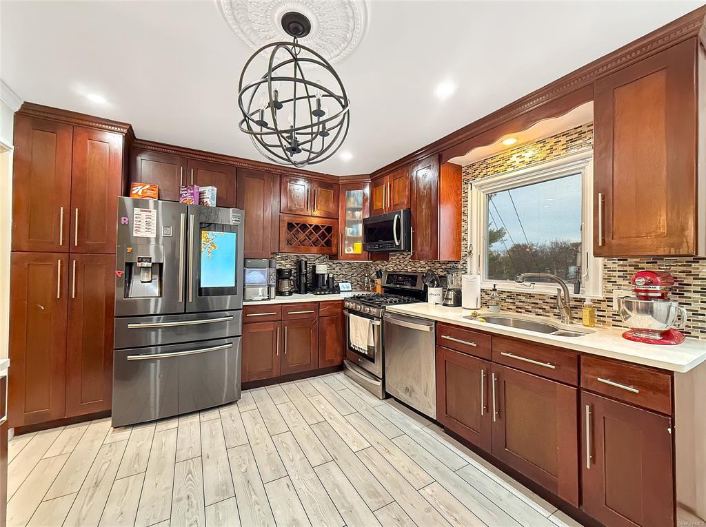 Kitchen featuring pendant lighting, sink, a notable chandelier, light hardwood / wood-style floors, and stainless steel appliances