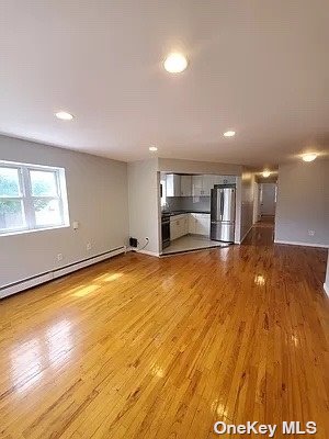 a view of empty room with kitchen and window