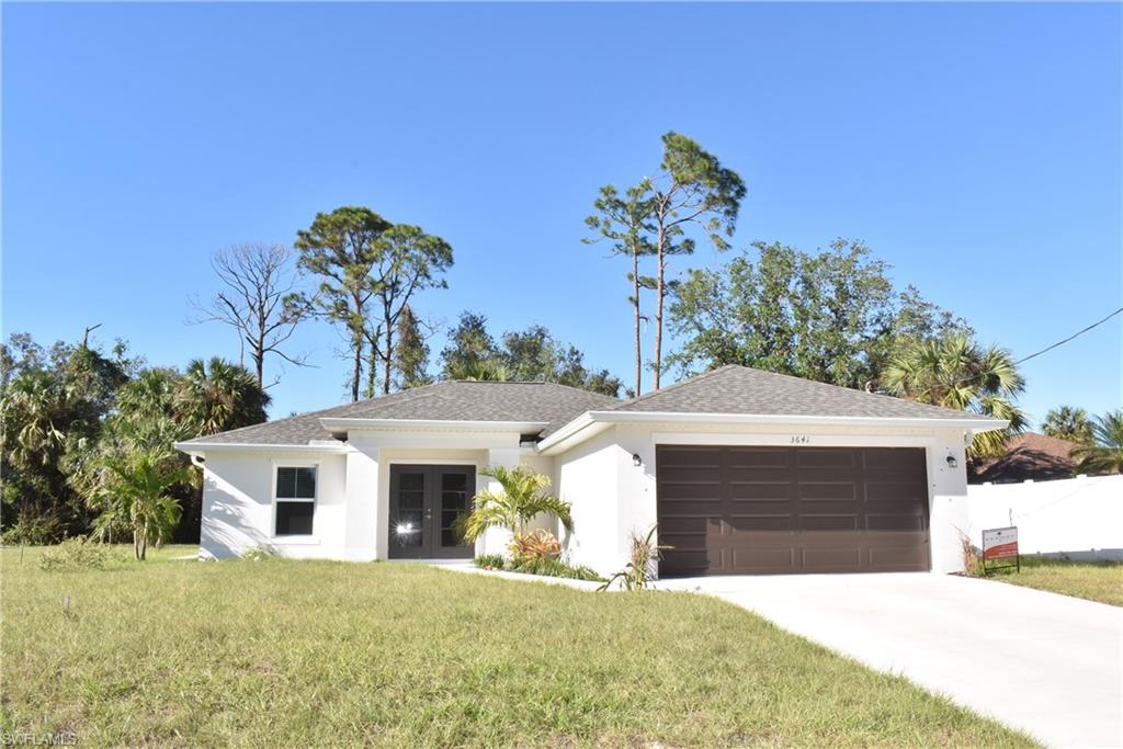 Single story home with french doors, a garage, and a front lawn