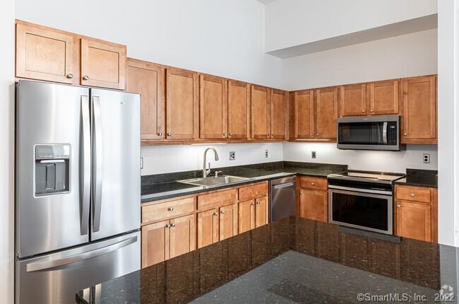 a kitchen with granite countertop a refrigerator stove and microwave