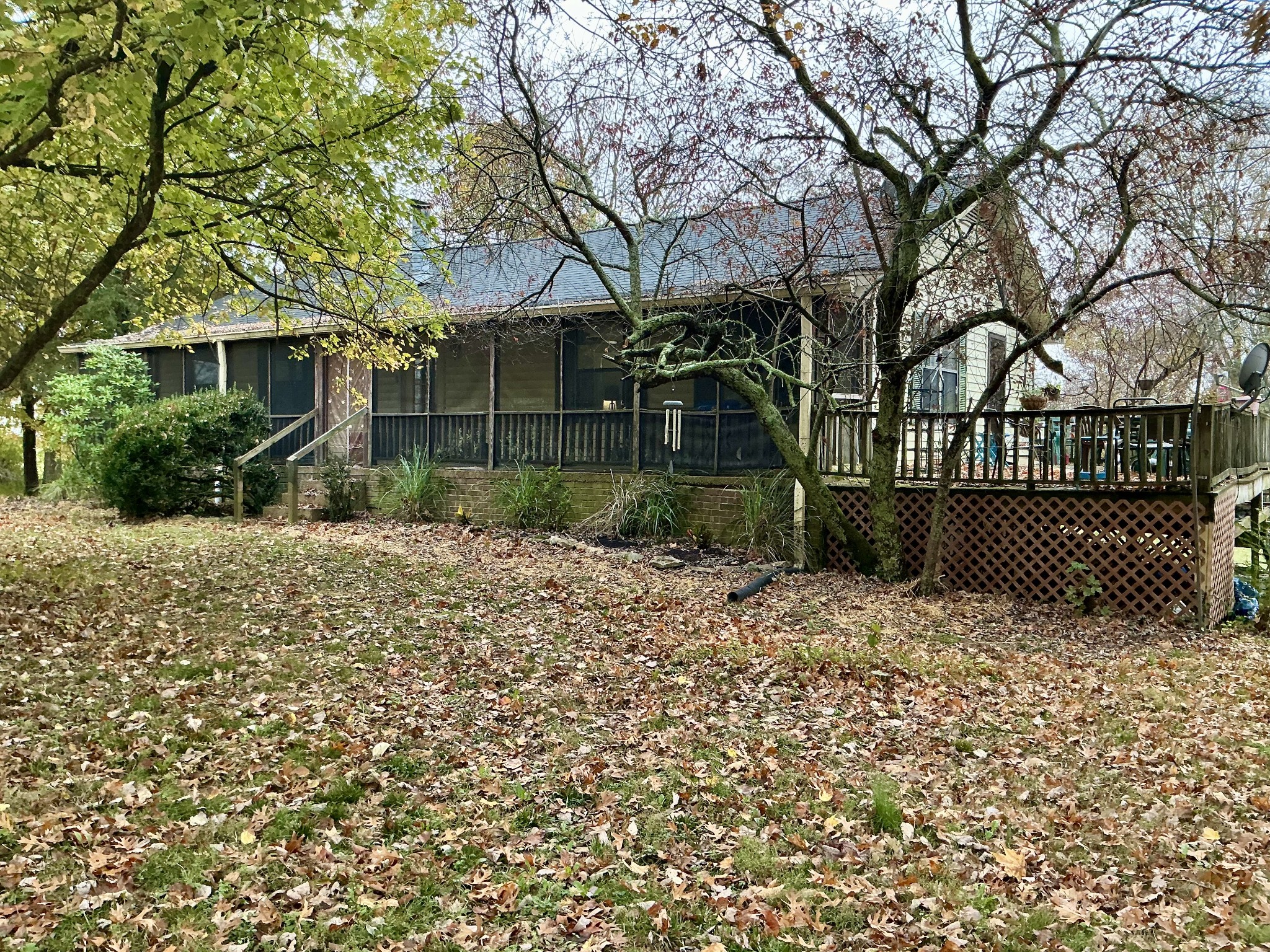 a view of a white house next to a yard with large trees