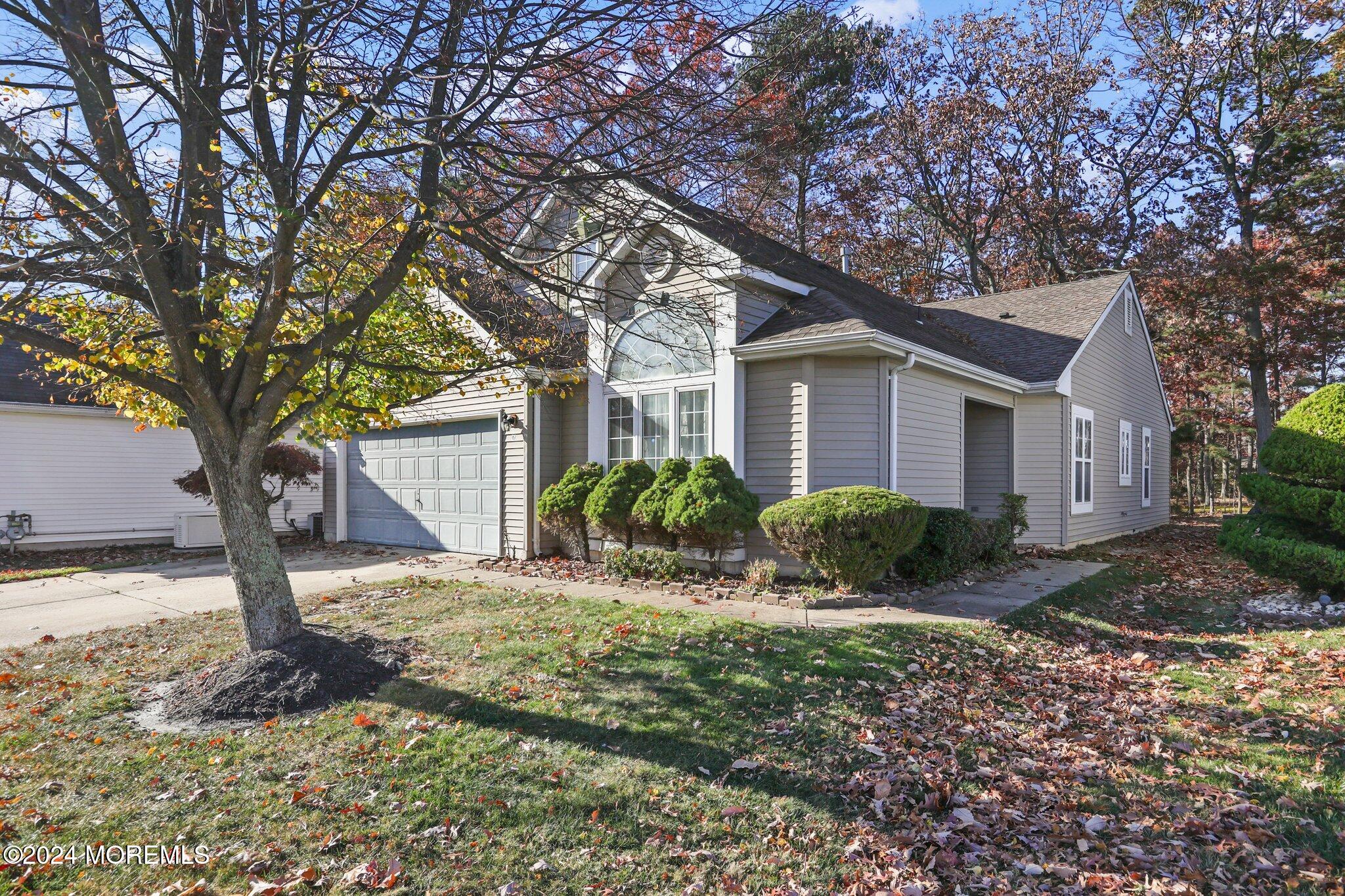 a front view of a house with garden and trees