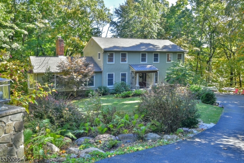 a view of a white house with a yard plants and large tree