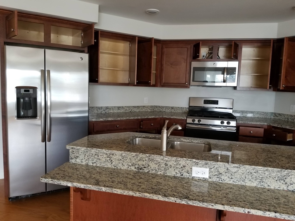 a kitchen with stainless steel appliances granite countertop a sink a stove and a refrigerator