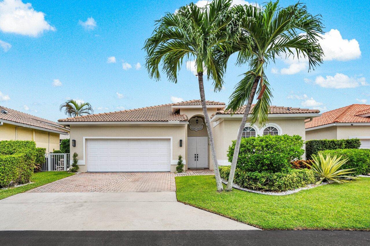 a front view of a house with a garden and palm trees