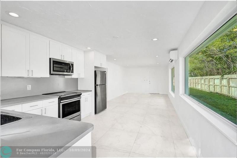 a kitchen with stainless steel appliances granite countertop a stove a sink and a refrigerator with white cabinets