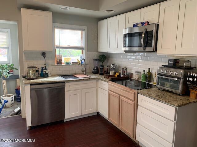 a kitchen with stainless steel appliances white cabinets a sink a stove a microwave and wooden floors