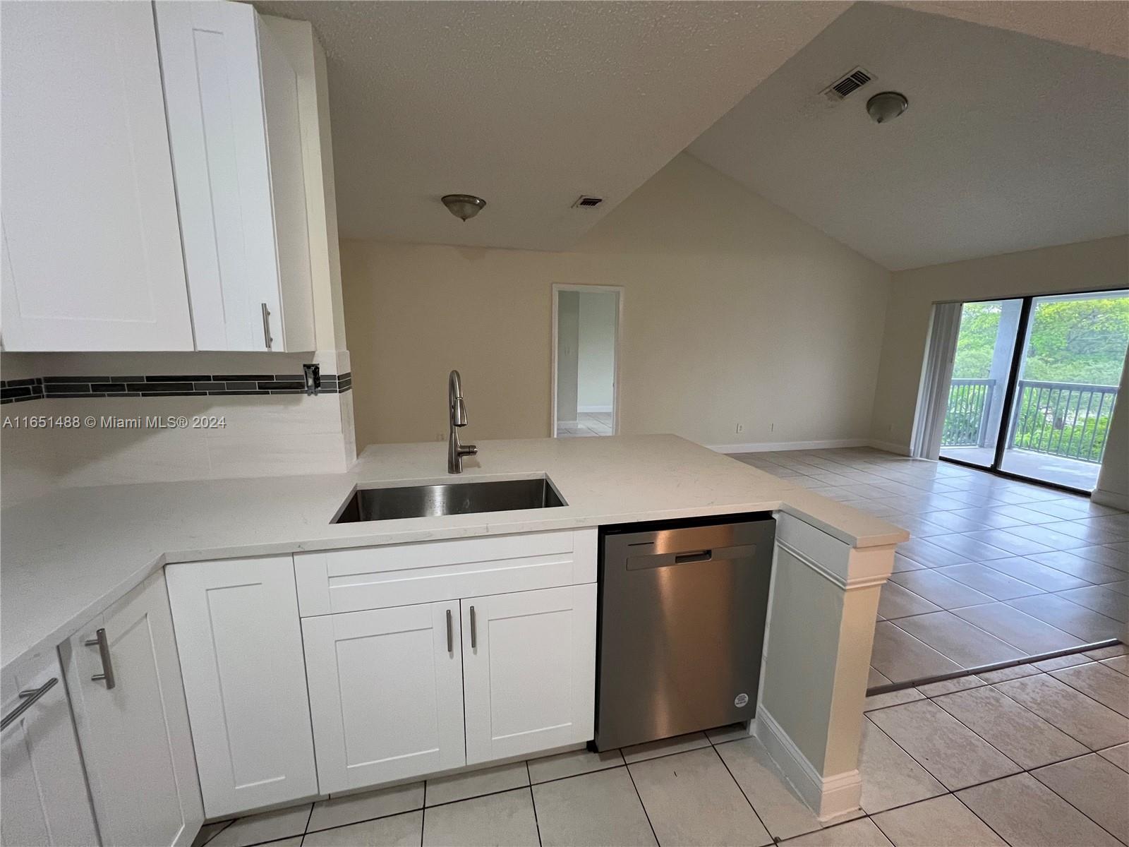 a kitchen with white cabinets and sink