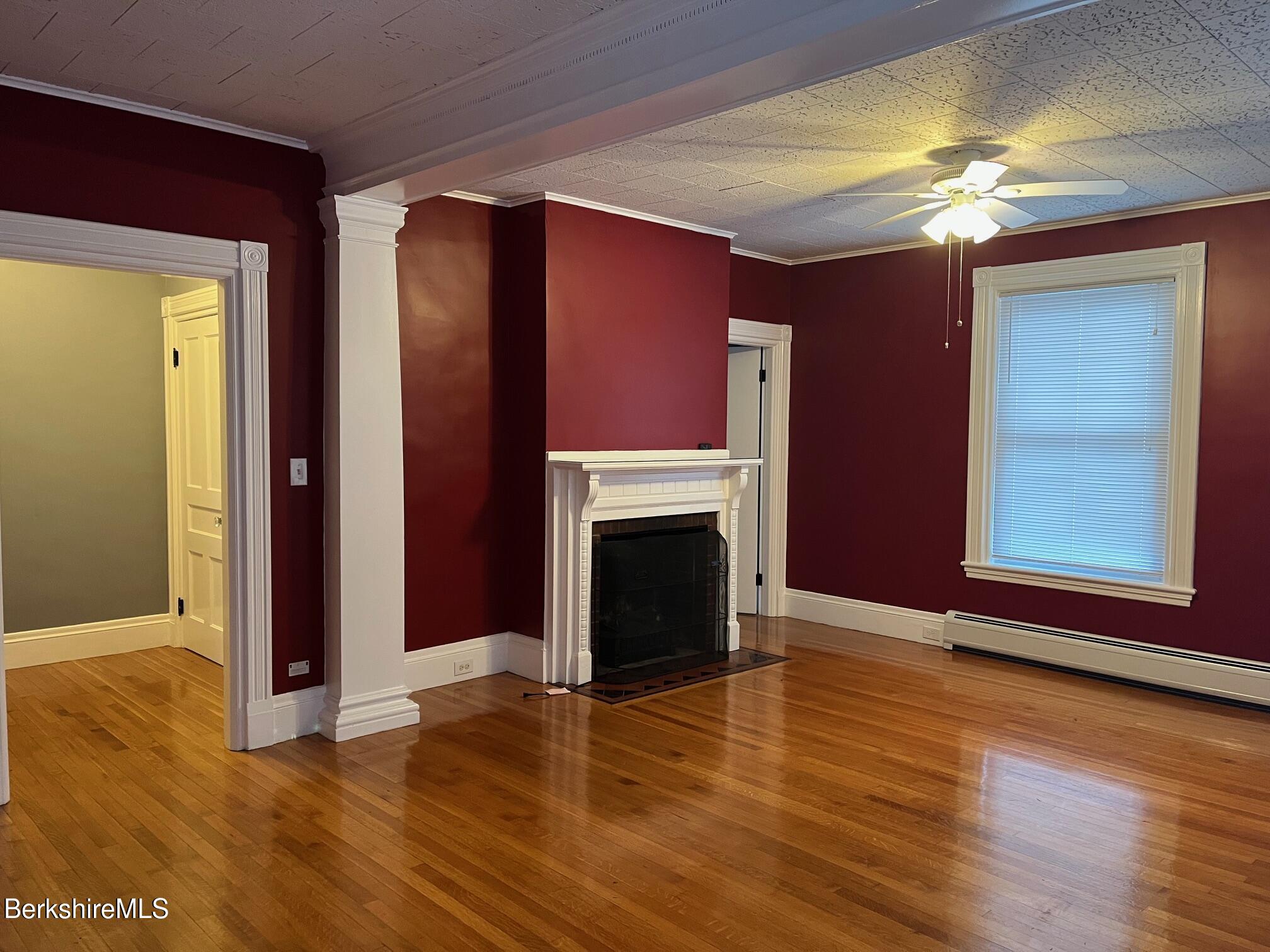 wooden floor fireplace and windows in an empty room