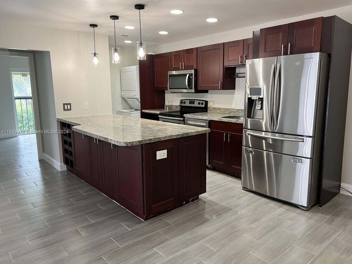 a kitchen with stainless steel appliances granite countertop a refrigerator a stove a sink and a microwave