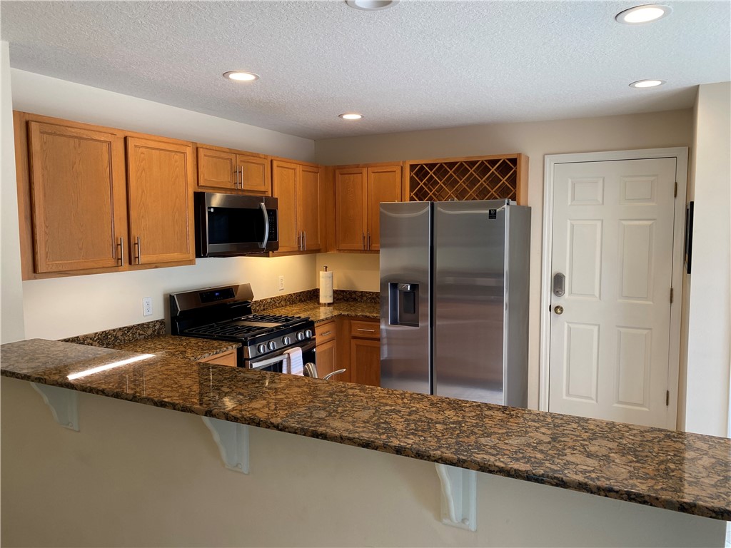 a kitchen with stainless steel appliances granite countertop a refrigerator a stove and a sink with wooden floor