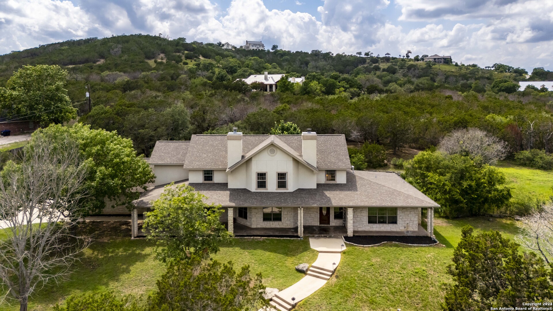 an aerial view of a house with swimming pool and mountains