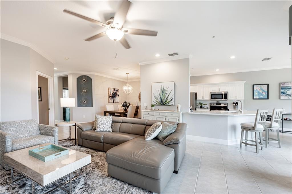 Living room with sink, crown molding, light tile patterned floors, and ceiling fan