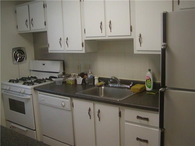 a kitchen with stainless steel appliances granite countertop white cabinets and a sink