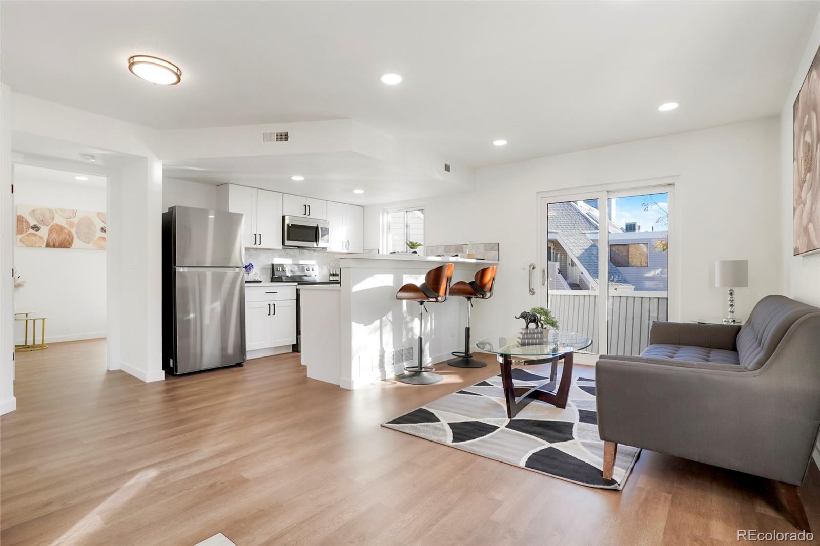 a living room with furniture and kitchen view with wooden floor