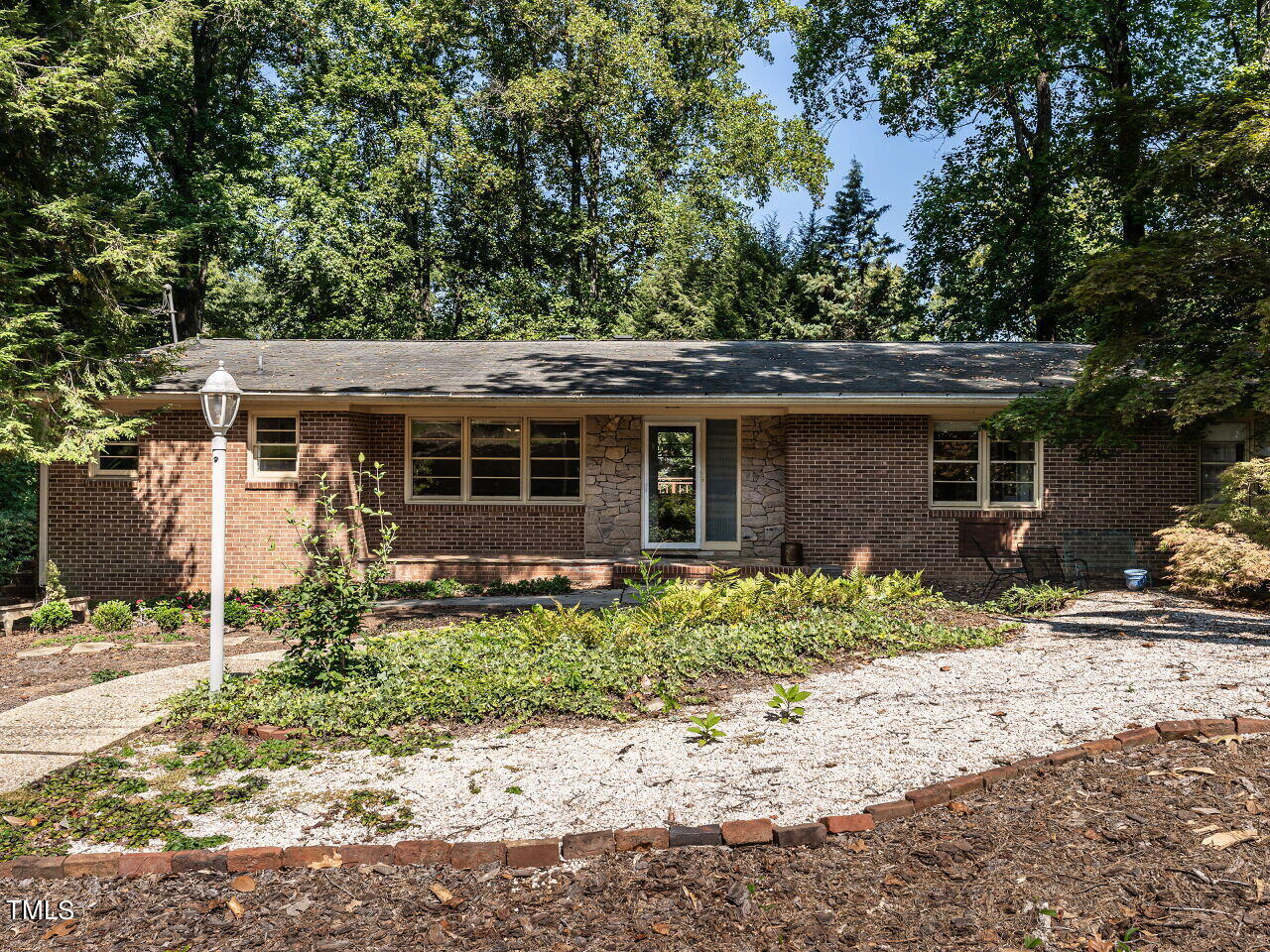 a front view of a house with a yard covered with trees