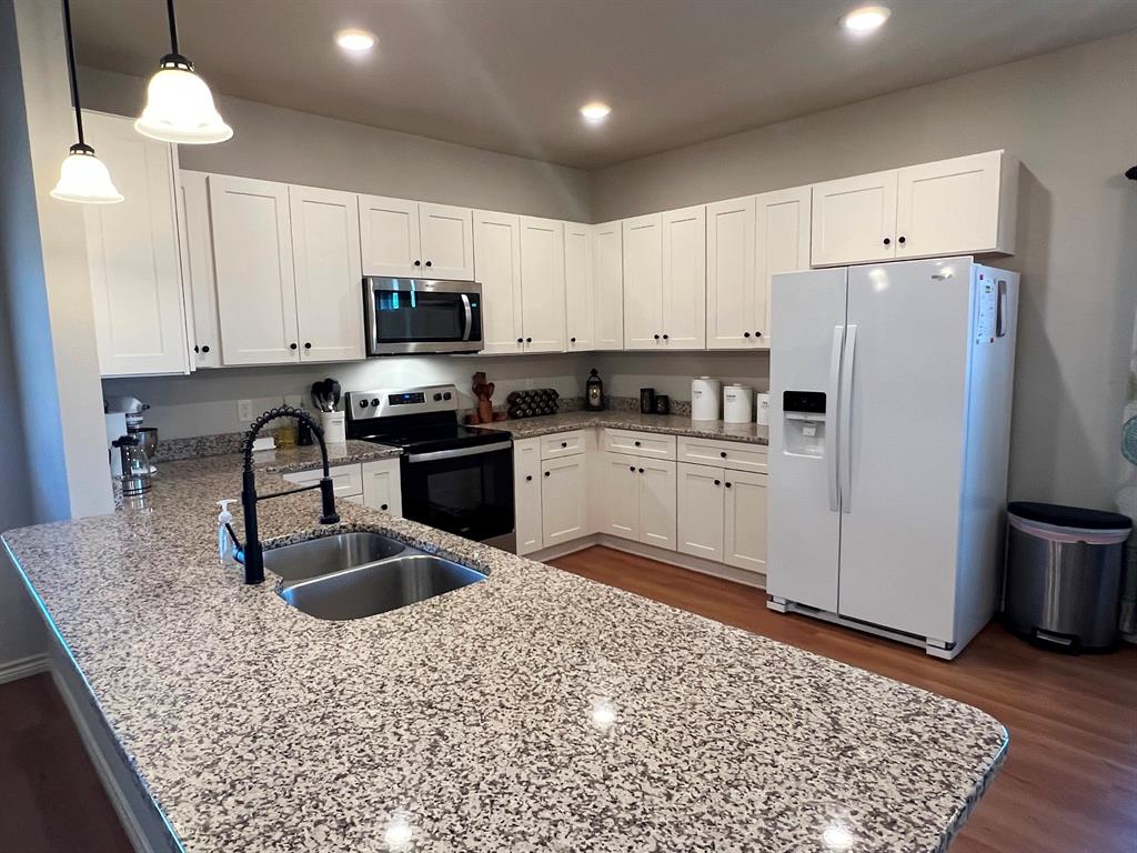 a kitchen with stainless steel appliances granite countertop a sink refrigerator and cabinets