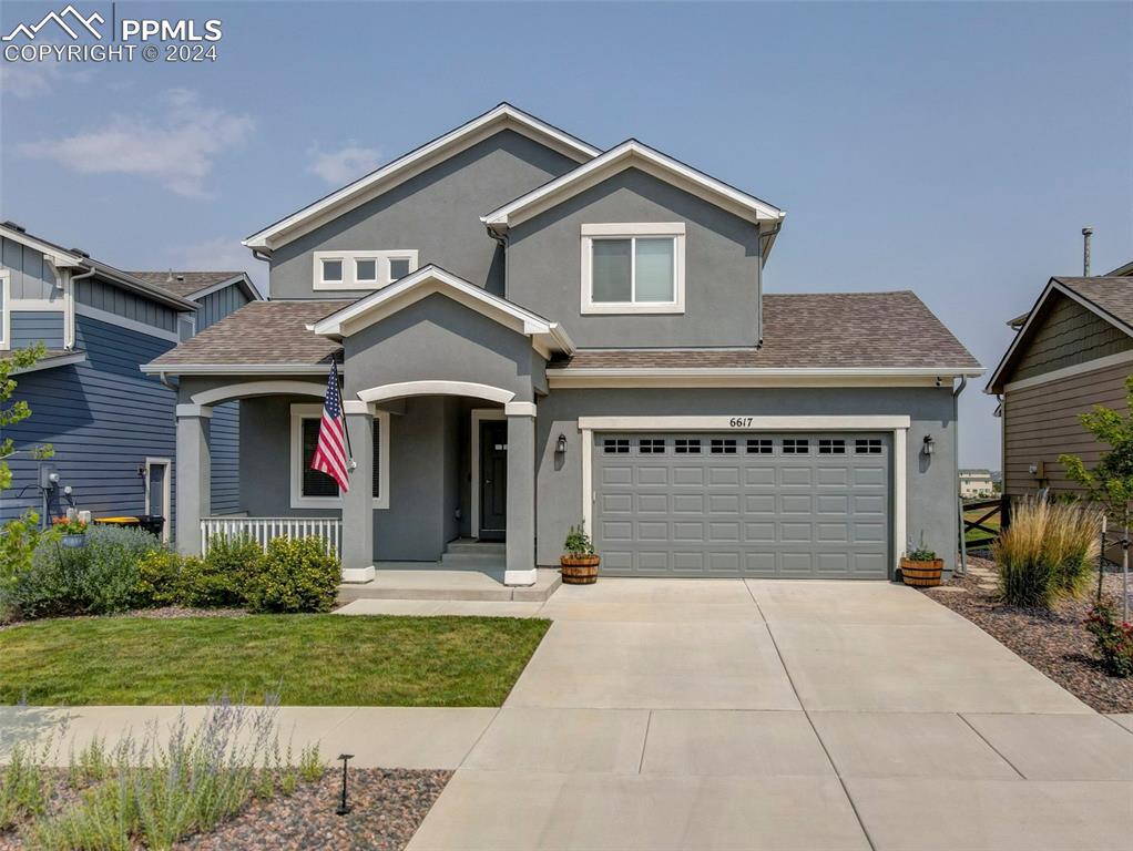 View of front of property featuring a garage and a front lawn