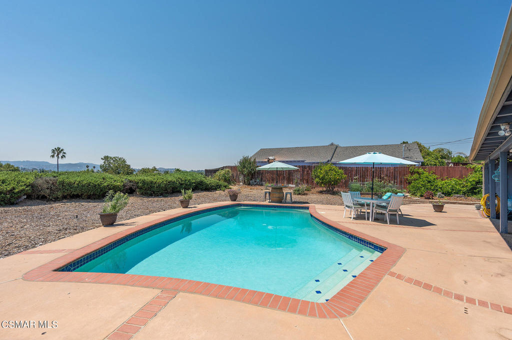 a view of a swimming pool with lawn chairs under an umbrella