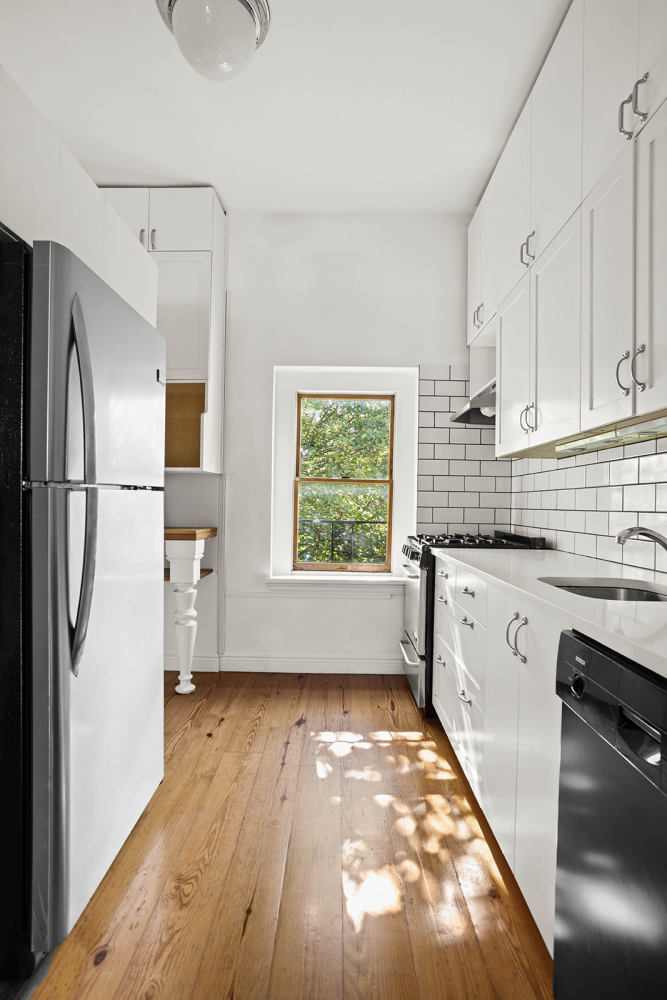 a kitchen with a refrigerator a sink and wooden floor