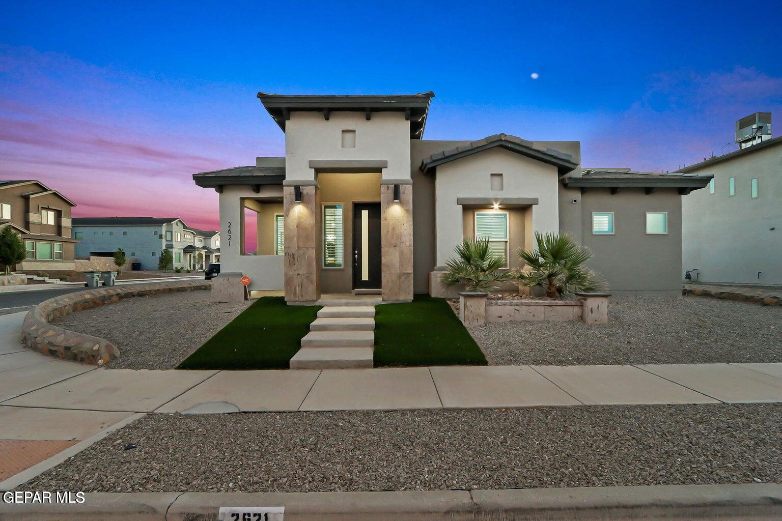 a front view of a house with garage and plants