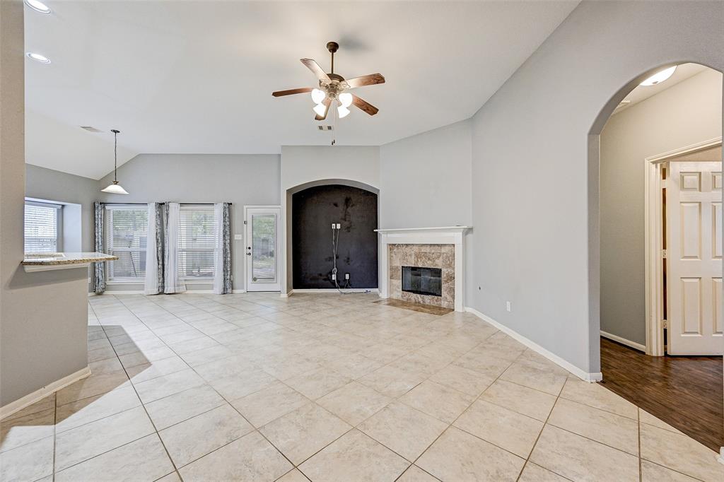 an empty room with chandelier fan and windows