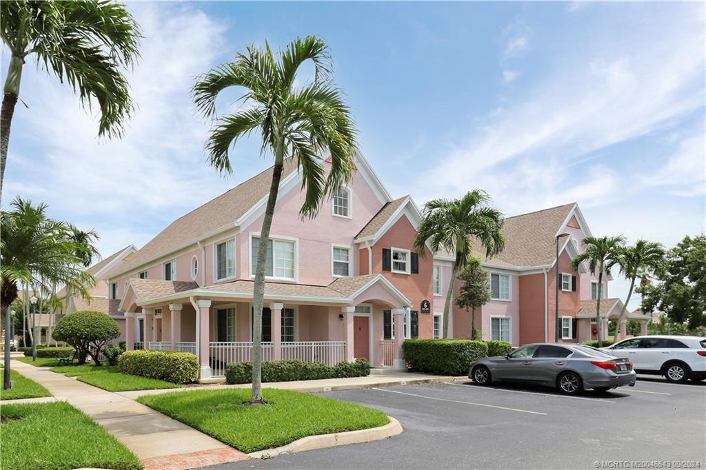 a front view of a house with a garden and palm tree