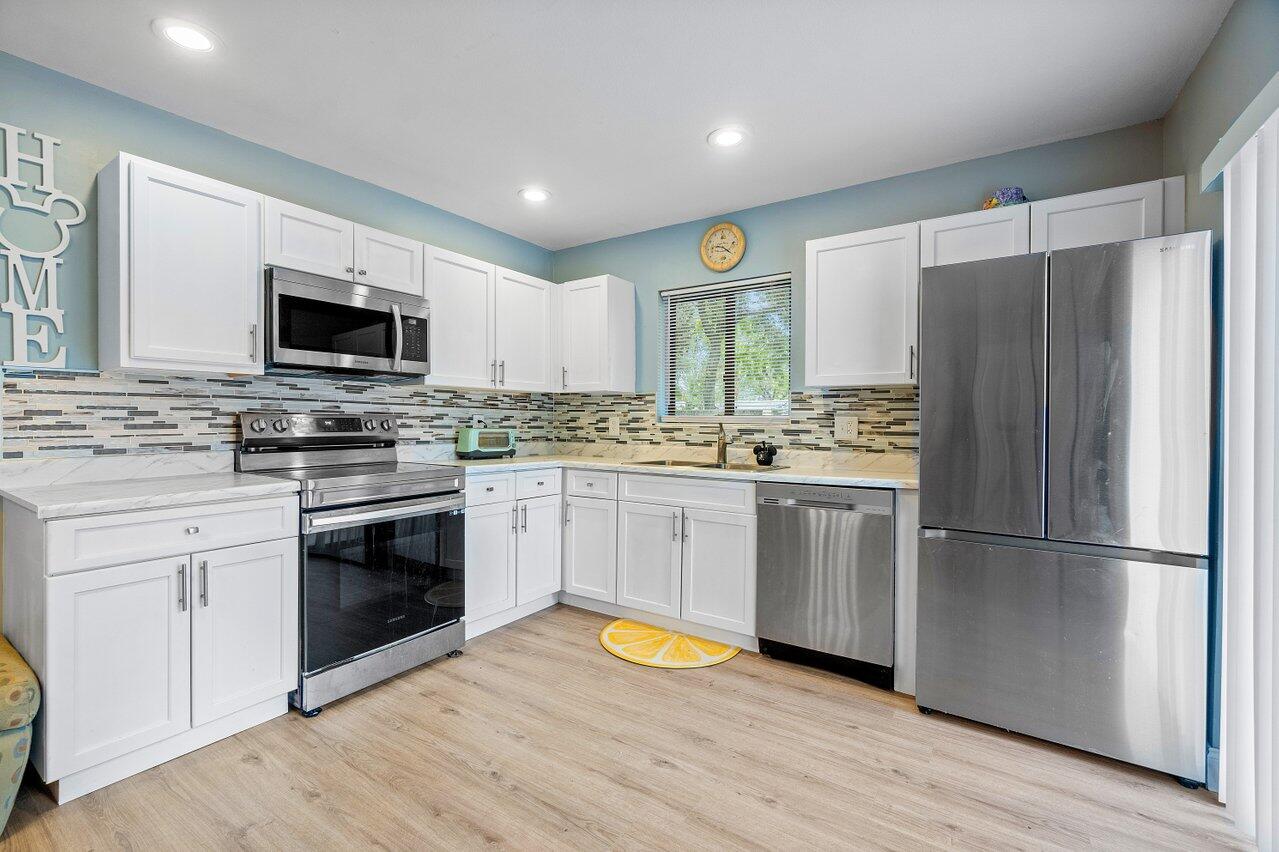 a kitchen with a refrigerator stove and wooden floor