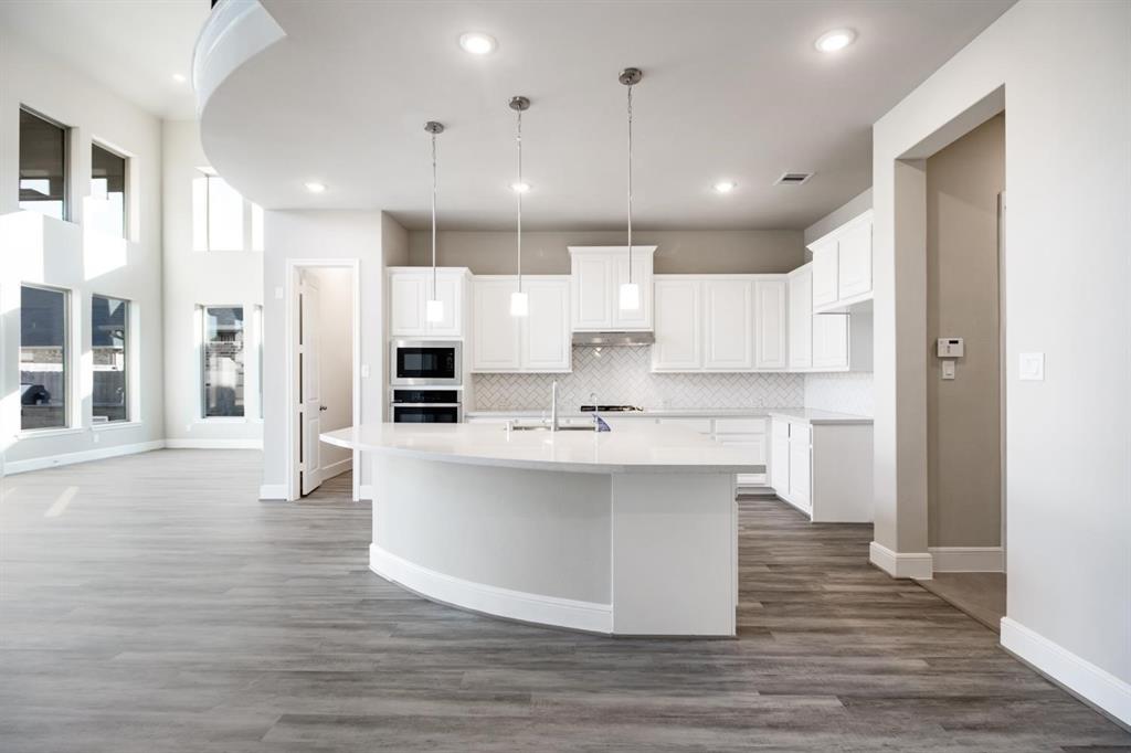 a large white kitchen with kitchen island a sink appliances and a counter top space