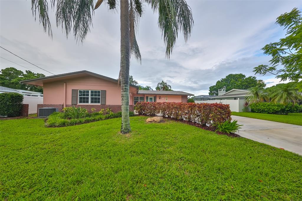 a view of a house with a big yard and palm trees