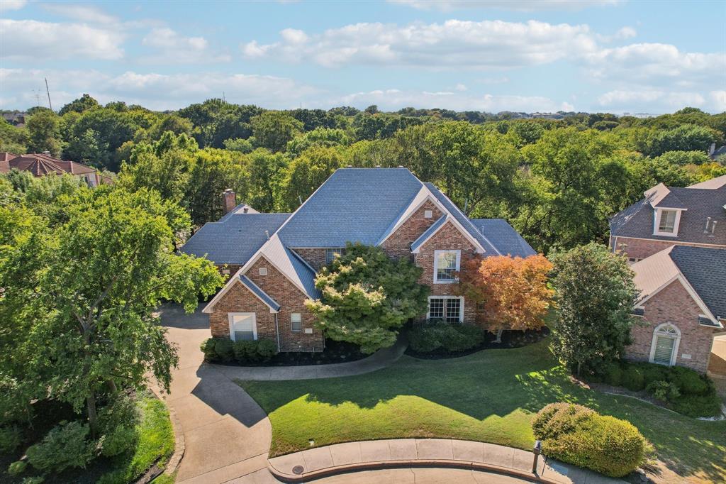 a view of a big house with a big yard plants and large trees