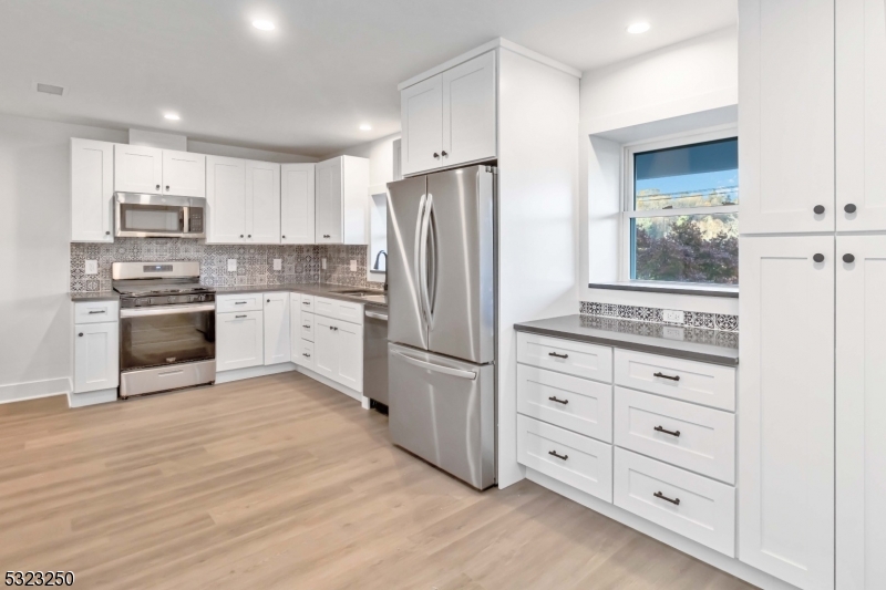 a kitchen with stainless steel appliances granite countertop a refrigerator stove and white cabinets