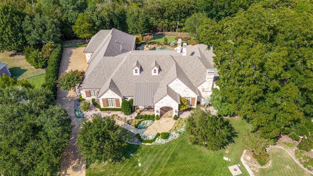 an aerial view of a house with a yard and trees all around