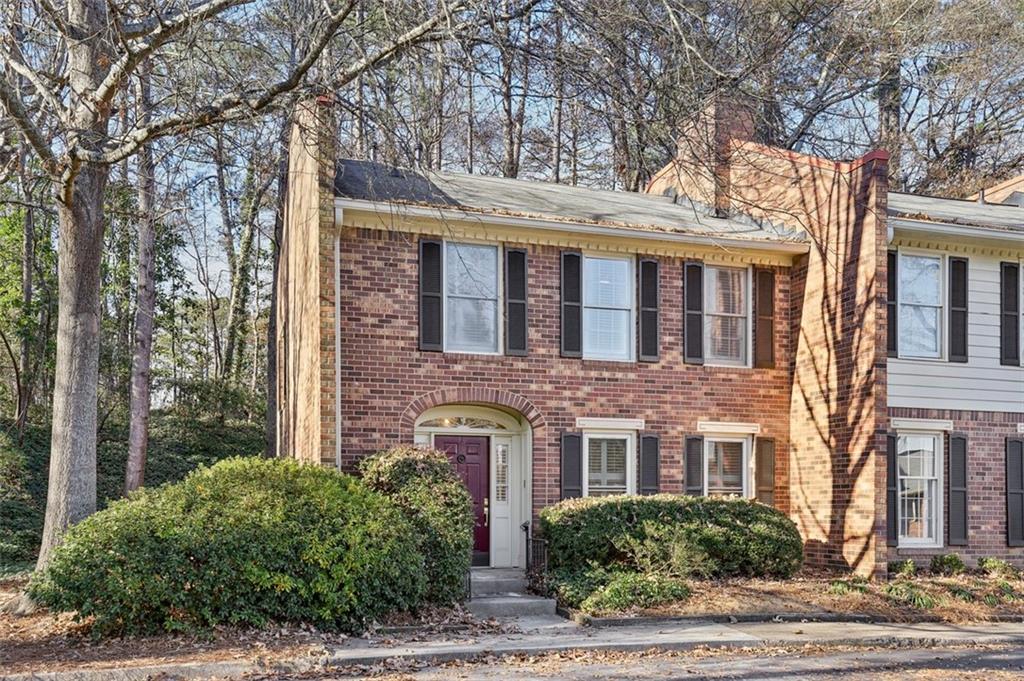 a front view of a brick house with a yard and plants