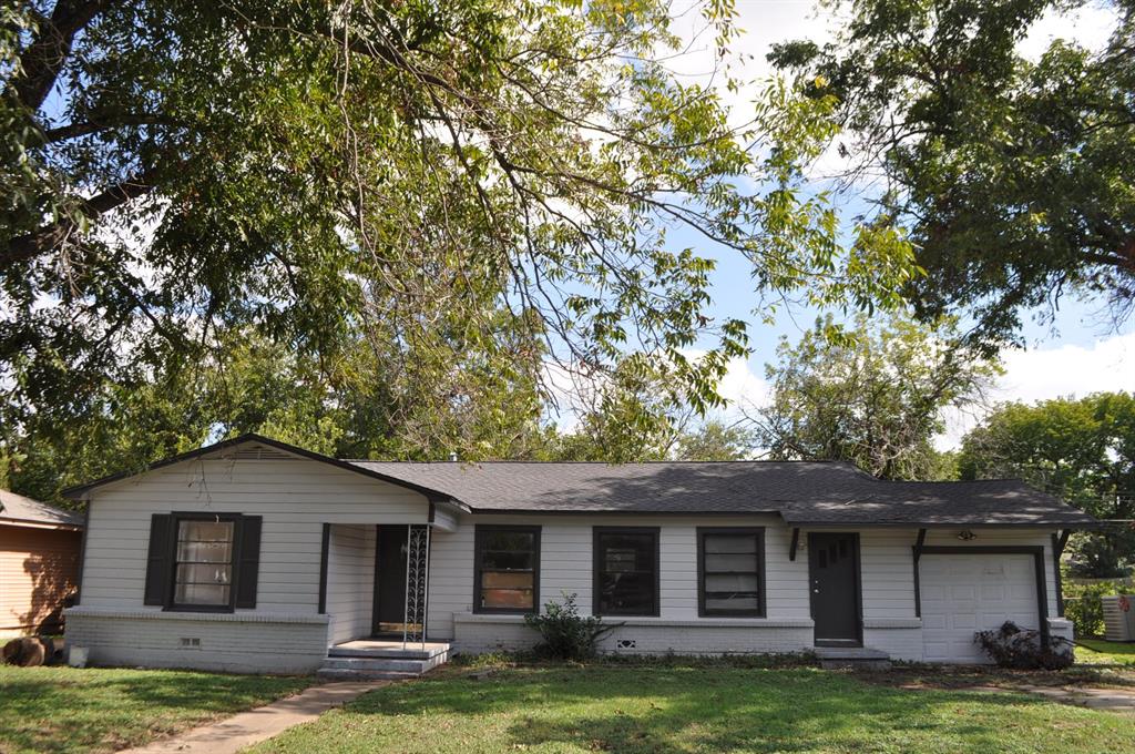 a front view of a house with a garden and trees