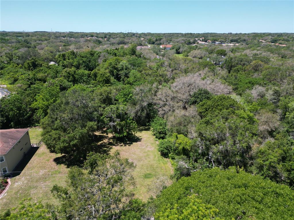 an aerial view of residential house with outdoor space and trees all around